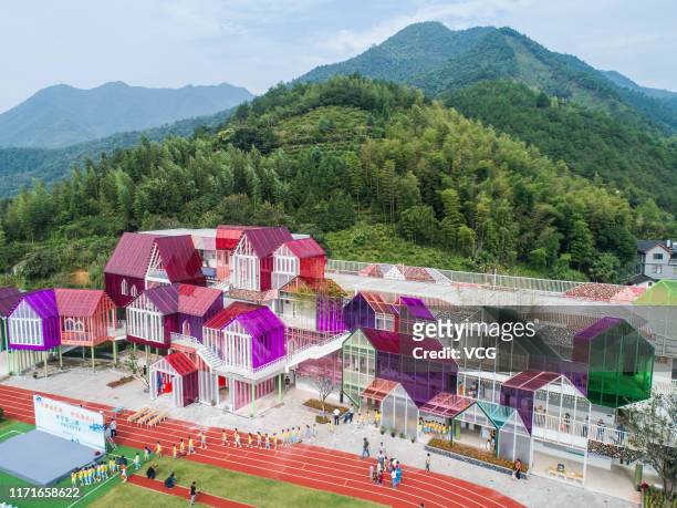 Aerial view of students walking on playground in front of a plexiglass-made school building on the first day of a new term at a primary school at...
