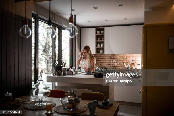 hermosa mujer joven usando teléfono rotativo en la cocina - teléfono con cable fotografías e imágenes de stock