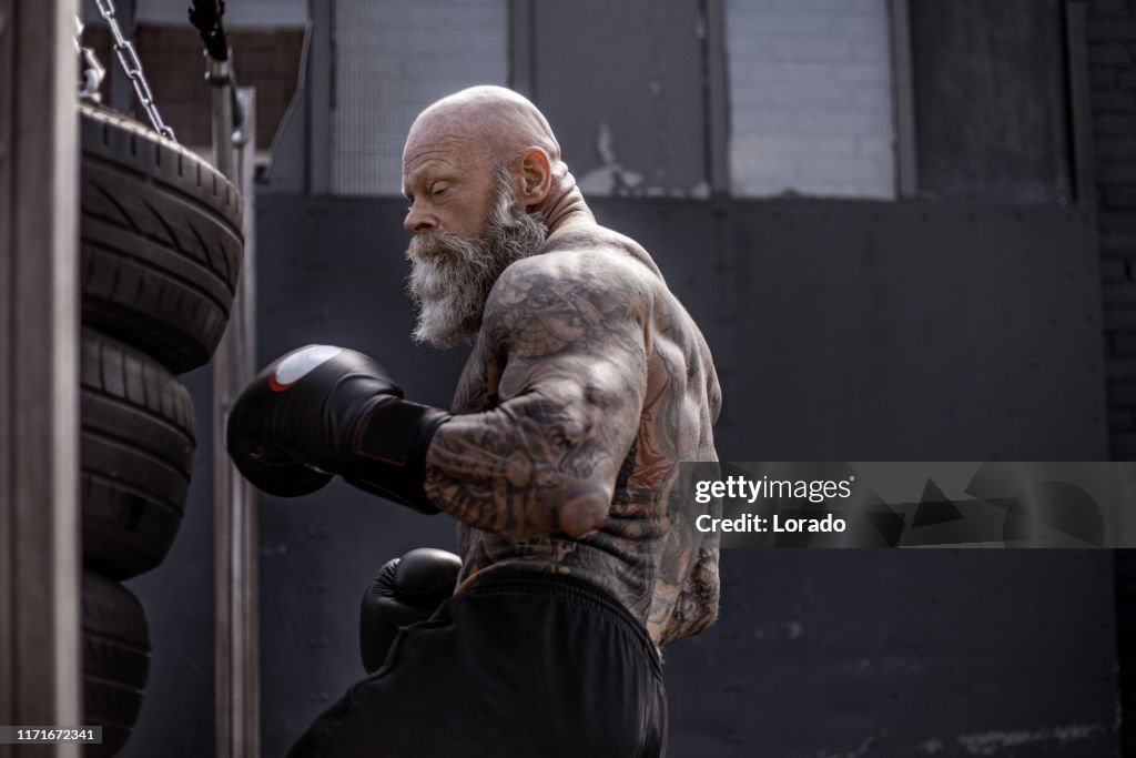 Tattooed Senior Boxer During Fighting Workout