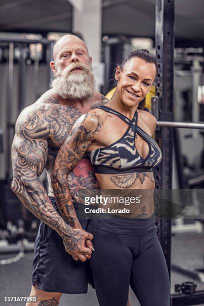 tattooed senior couple during gym workout - senior athlete stock pictures, royalty-free photos & images
