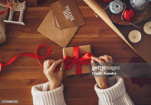 mujer envolviendo un regalo de navidad - desenvolver fotografías e imágenes de stock
