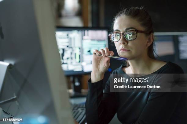 kvinna övervakar mörkt kontor - computer hacker bildbanksfoton och bilder