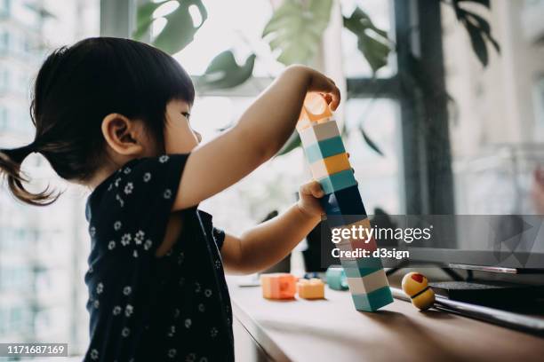 creative little toddler girl playing with colourful building blocks at home - baby toys stock-fotos und bilder