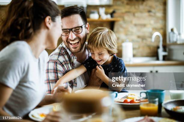 young cheerful family having fun at dining table. - family dinner stock pictures, royalty-free photos & images