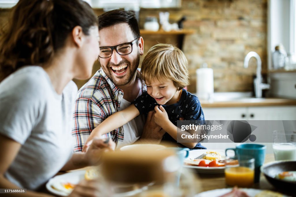 Young cheerful family having fun at dining table.