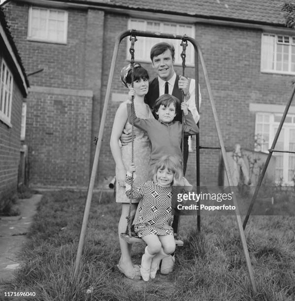 English pop singer Marty Wilde with his wife Joyce and children, Ricky Wilde and Kim Wilde, together on a swing in the garden of their home in May...