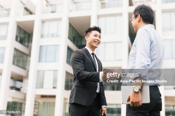 zwei zufriedene asiatische geschäftsleute schütteln händend. - handshaking in a bank stock-fotos und bilder