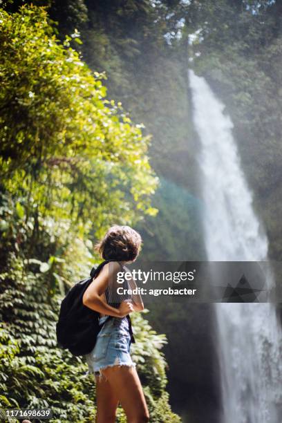 beautiful brunette woman enjoying near waterfall - bali waterfall stock pictures, royalty-free photos & images