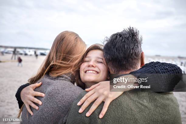 happy girl hugging woman and man on the beach - kids hug stock-fotos und bilder