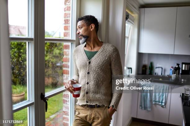 pensive man looking out of window - daydreaming sad stock pictures, royalty-free photos & images