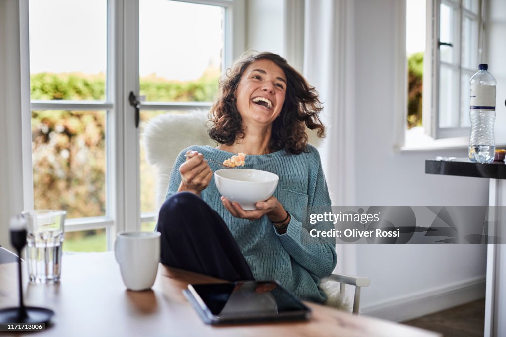 Happy woman having breakfast at dining table