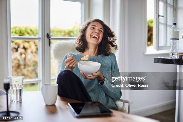 happy woman having breakfast at dining table - eating food happy stockfoto's en -beelden