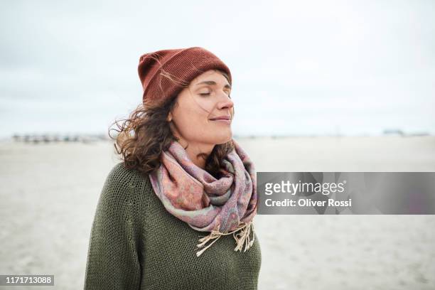 portrait of smiling woman with closed eyes on the beach - tranquility stock-fotos und bilder