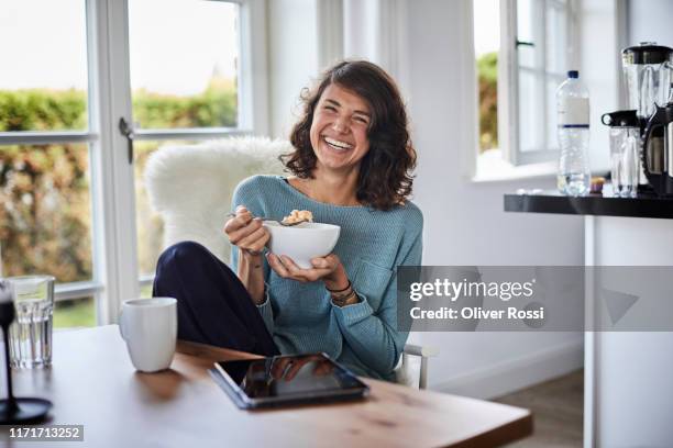 happy woman having breakfast at dining table - breakfast cereal fotografías e imágenes de stock