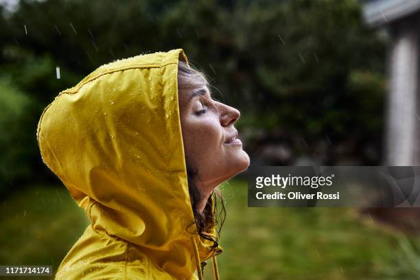 woman wearing raincoat during heavy rain in garden - huva bildbanksfoton och bilder