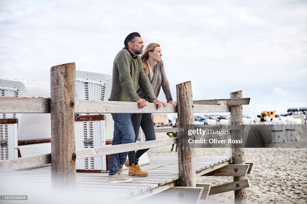 Father and adult daughter standing on boardwalk on the beach