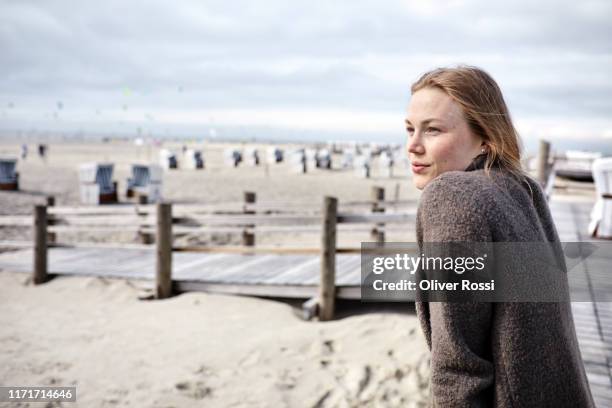 young woman on the beach looking at view - strandkorb stockfoto's en -beelden