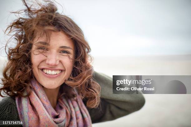 portrait of happy woman with windswept hair on the beach - hair flying stock-fotos und bilder