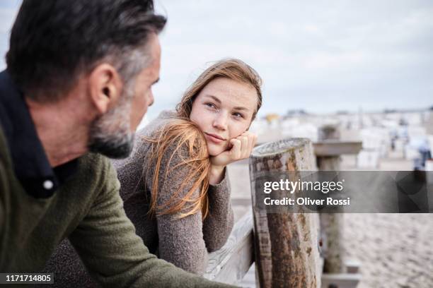 adult daughter looking at father on boardwalk on the beach - older man stock pictures, royalty-free photos & images