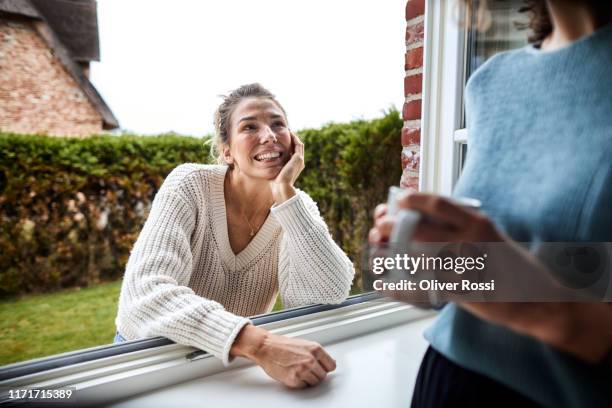 smiling woman looking at friend through the window - open window frame stock pictures, royalty-free photos & images