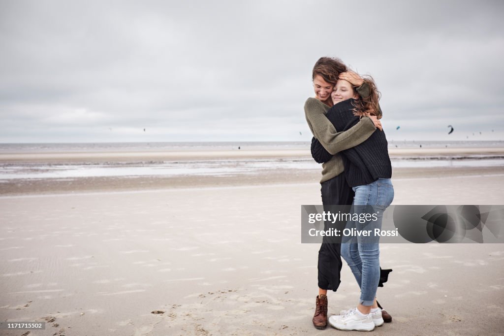 Happy young woman hugging girl on the beach
