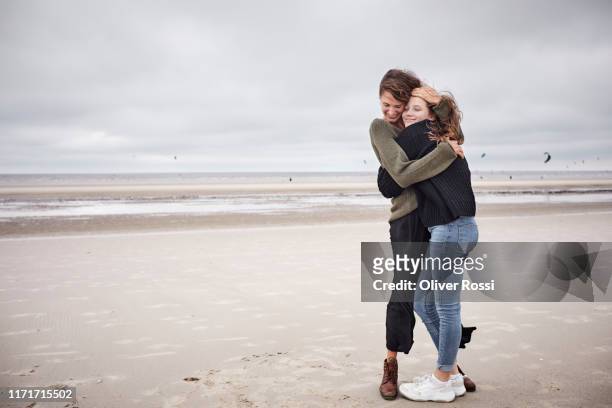happy young woman hugging girl on the beach - embracing stock pictures, royalty-free photos & images