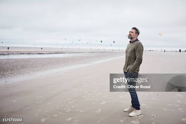 pensive man standing on the beach - stehen stock-fotos und bilder
