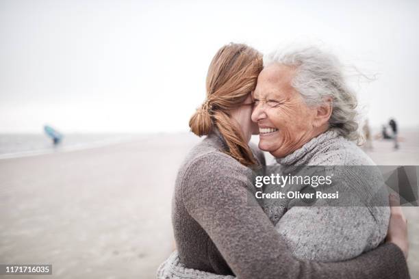 affectionate grandmother and granddaughter hugging on the beach - beach concept stock-fotos und bilder