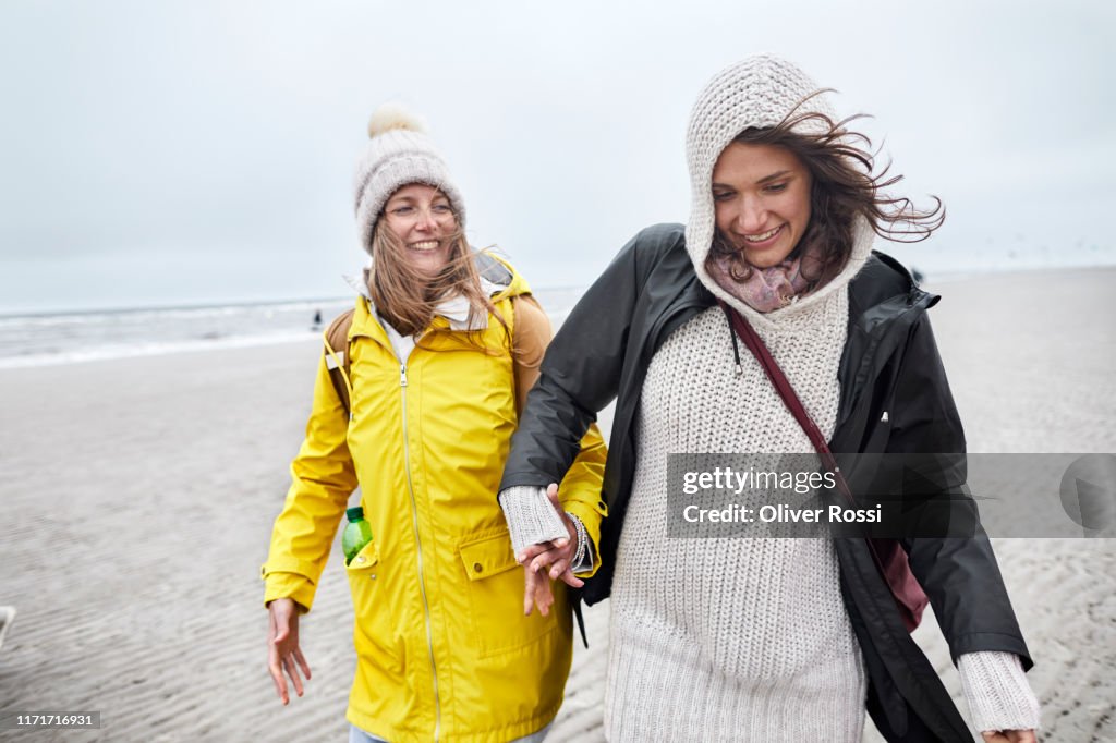 Two happy women in warm clothing on the beach