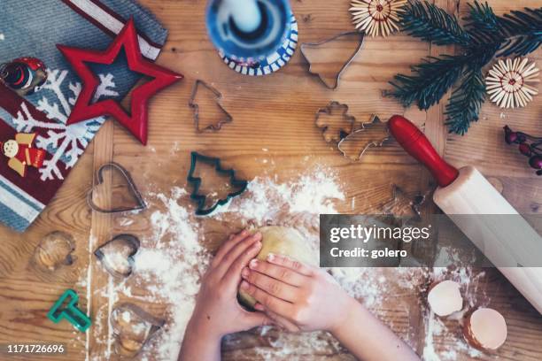 kind backt weihnachtsplätzchen auf holztisch - advent stock-fotos und bilder