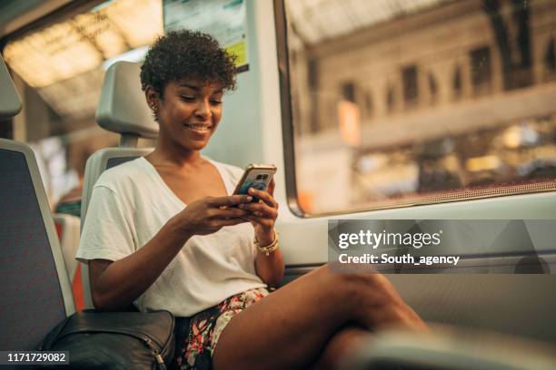 schöne frau mit telefon im zug - smartphone im zug stock-fotos und bilder