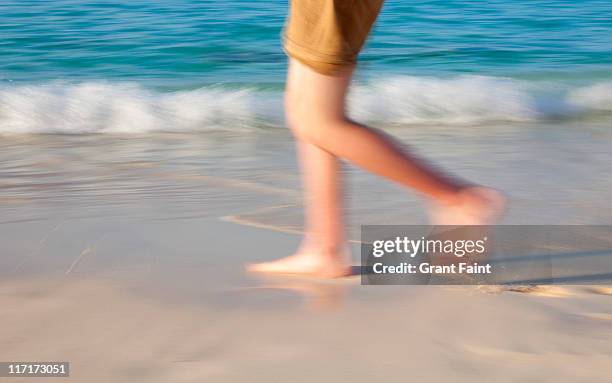 teenage boy walking along beach. - teen boy barefoot stock pictures, royalty-free photos & images