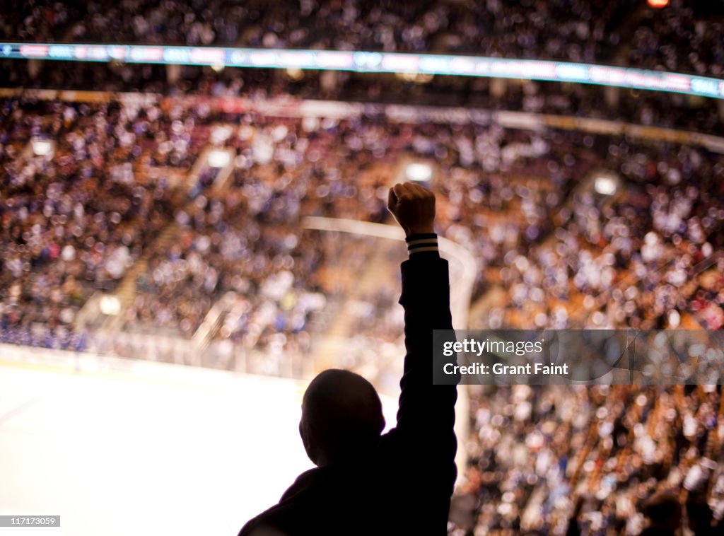 Man at hockey game cheering.