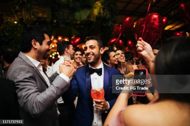 bruidegom en bruiloftsgasten lachen tijdens het feest - elegant cocktail party stockfoto's en -beelden