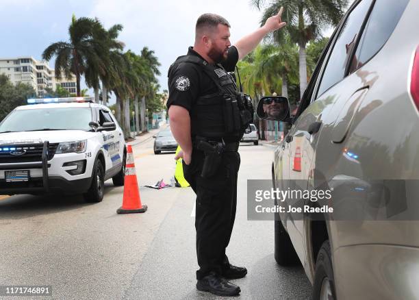Delray Beach police officer, Matt Warne, informs a driver that the road to the beach is only open to residents as Hurricane Dorian continues to make...