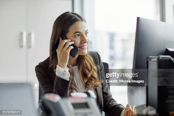 smiling businesswoman talking on mobile phone - businesswoman talking smartphone stock pictures, royalty-free photos & images