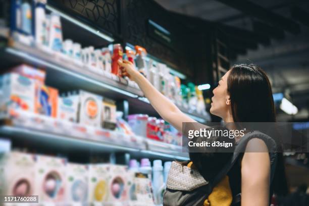 young asian mother grocery shopping with little daughter and choosing for baby necessities in a store - cosmetic testing store stock pictures, royalty-free photos & images