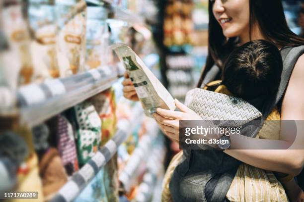 young asian mother grocery shopping with little daughter and choosing for organic baby food in the supermarket - tag 2 stock pictures, royalty-free photos & images