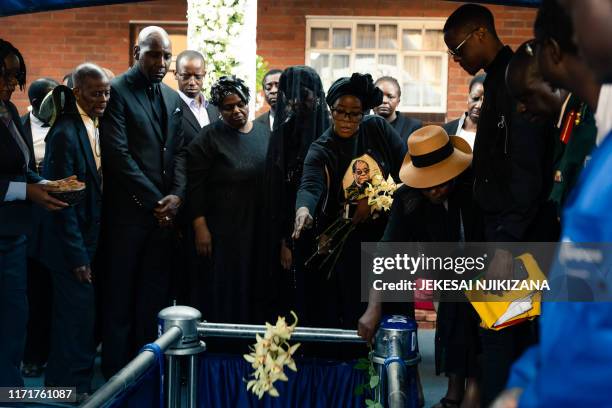 Bona Mugabe Chikore , daughter of former Zimbabwe president Robert Mugabe, throws flowers ontop of her fathers coffin next to her mother Grace Mugabe...