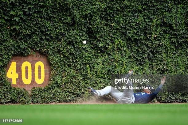 Jake Fraley of the Seattle Mariners falls in the ivy attempting to make a catch in the third inning against the Chicago Cubs at Wrigley Field on...