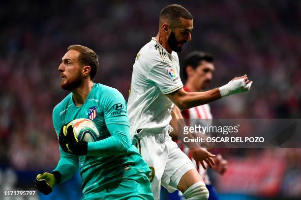 Real Madrid's French forward Karim Benzema challenges Atletico Madrid's Slovenian goalkeeper Jan Oblak during the Spanish league football match...
