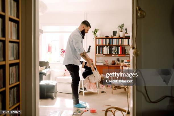 full length of father swinging daughter in living room at home - single father stockfoto's en -beelden