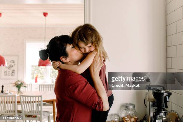 side view of mother kissing sad daughter at home - day 4 stockfoto's en -beelden