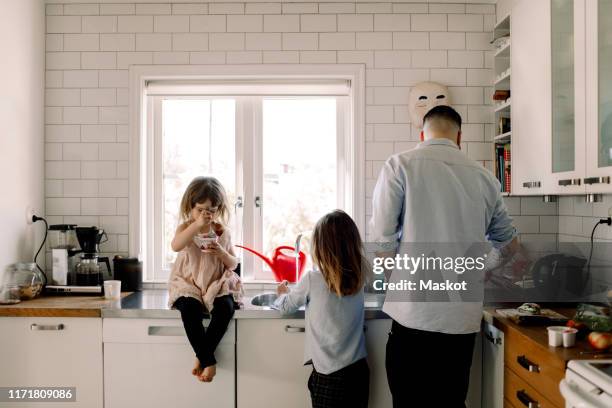 father and daughter working while girl eating food in kitchen at home - hipster in a kitchen stock-fotos und bilder