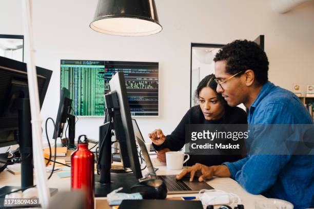 focused male and female engineers coding over laptop on desk in office - engineer stock pictures, royalty-free photos & images