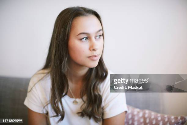 thoughtful teenage girl sitting at wellness center - stressed young woman sitting on couch stock-fotos und bilder