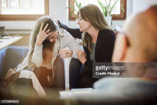 mother consoles daughter during therapy session at workshop - mom head in hands stock pictures, royalty-free photos & images