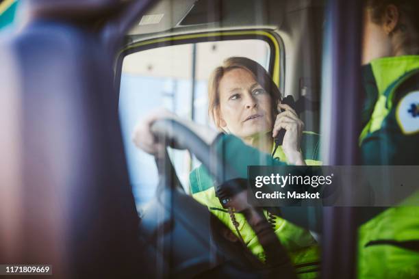 paramedic talking on phone while looking at coworker in ambulance - paramedic phone stock pictures, royalty-free photos & images