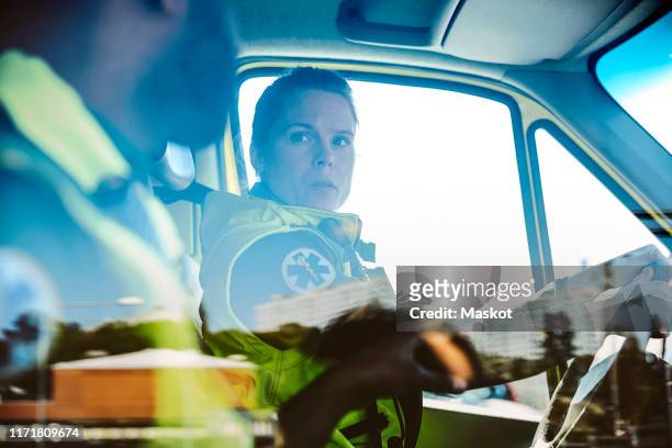 healthcare workers talking while sitting in ambulance - medical ambulance female stockfoto's en -beelden