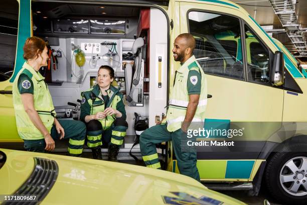 male and female paramedics talking while sitting in ambulance at parking lot - ambulance bildbanksfoton och bilder